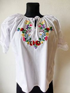 "This Hungarian traditional Kalocsa peasant blouse is the perfect addition to any boho or ethnic-themed wardrobe. With a beautiful floral pattern and intricate embroidery accents, this blouse will make you stand out in any crowd. Made from 100% cotton, this blouse has short sleeves and a collarless design, making it both comfortable and stylish. The blouse comes in XL size, perfect for a regular fit. This blouse is a great basic piece that can be dressed up or down for any occasion. Condition:new Size: L Bust 120cm(2 pieces) /47\" XL Bust 124cm/ 48.8\" International sizes:        XSS        M         LXL                 34 36/38 38/40 42 44  More from my shop: https://theoldworldvintage.etsy.com/listing/1561370024 Please,check my home decor shops : https://www.etsy.com/shop/HajniVintage Ka Folk Blouse With Multicolor Embroidery Motif, Folk Style Peasant Top With Boho Collar For Spring, White Boho Collar Peasant Top, White Peasant Top With Boho Collar, Folk Style Short Sleeve Peasant Top With Embroidered Border, Folk Style Peasant Top With Embroidered Border, Folk Peasant Top With Multicolor Embroidered Neckline, Traditional White Peasant Top With Intricate Embroidery, White Hippie Peasant Top For Festival