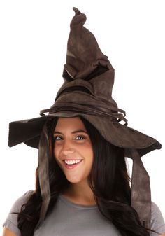 a woman wearing a brown witches hat with her hair in the air and smiling at the camera