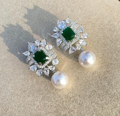 Emerald Earrings in Pearl Drop, a graceful blend of charm and sophistication. Adorn yourself in the regal allure of Green Diamond and Emerald Earrings, complemented by the timeless beauty of Pearl Diamond designs. Our Faux Emerald Statement Studs, inspired by Harry Winston, add a touch of luxury. For a classic finish, embrace the refinement of Pearl Drop Earrings, completing your ensemble with the brilliance of our American Diamond earrings for an inspired and radiant look. *𝐏𝐑𝐎𝐃𝐔𝐂𝐓 𝐃𝐄𝐓𝐀𝐈𝐋* * Material: Brass * Plating: White Rhodium Plated * Stone: AAA Quality CZ Diamond, Pearl & Emerald. *𝐃𝐈𝐌𝐄𝐍𝐒𝐈𝐎𝐍𝐒* * Weight: 14 gm each * Length: 2 Inches * Width: 1.5 Inches *𝐒𝐇𝐈𝐏𝐏𝐈𝐍𝐆 𝐏𝐎𝐋𝐈𝐂𝐘* * Shipping: worldwide from India. * Free shipping: All our products have a f Emerald Diamond Earrings, Earrings Luxury, Emerald Wedding, Pearl And Diamond Earrings, Harry Winston, Pearl Earring, Earrings Studs, Green Diamond, Emerald Earrings