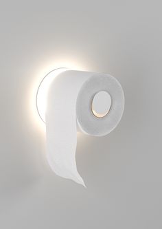 a roll of toilet paper sitting on top of a white wall next to a light