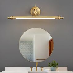 a bathroom with a sink, mirror and gold faucet on the wall above it