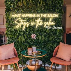 two chairs and a table in front of a green wall that says, what happens in the salon stays in the salon?