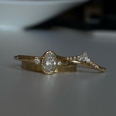 two gold wedding rings with diamonds on them sitting on a counter top next to a bowl