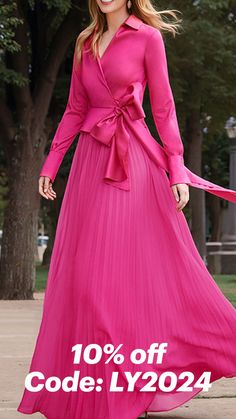 a woman in a long pink dress is holding a red ribbon and smiling at the camera