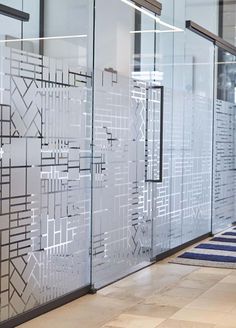 an office hallway with glass partitions and blue rug on the floor next to it