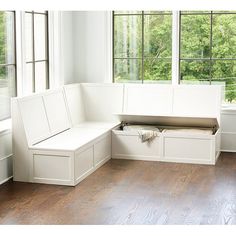 a white bench sitting in the middle of a living room next to two large windows