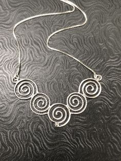 I like spirals and in Celtic lore, they can represent going from stages of oneself primal points to enlightenment, and though most of us have a way to go, we can at least adorn one in hopes of always continuing on a path of growth and self-reflection. This Celtic Spiral Necklace, in sterling silver, with each scroll hand-made in alternating plain and twist 16 gauge wire, embodies Celtic symbolism. I wanted to fabricate something meaningful and magical within the spirit of these ancient symbols. Unique Spiral Sterling Silver Necklace, Silver Spiral Bohemian Necklace, Bohemian Silver Spiral Necklace, Adjustable Spiral Necklace Nickel Free, Adjustable Spiral Nickel-free Necklace, Spiral Wire Wrapped Sterling Silver Necklace, Handmade Spiral Silver Necklace, Unique Silver Spiral Necklace, Artistic Spiral Wire Wrapped Jewelry