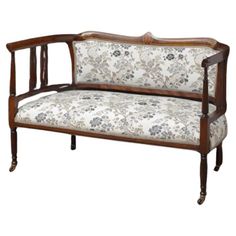 an antique wooden bench with floral fabric upholstered on the armrests and back