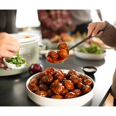 two people are serving food to each other at a table with plates and bowls on it