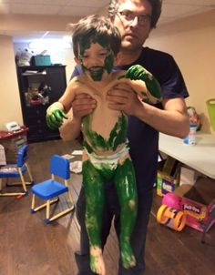 a man holding a child covered in green paint