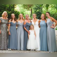 a group of women standing next to each other in long dresses and one girl wearing a white dress