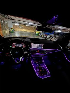 the interior of a car is lit up with purple lights and steering wheel controls,