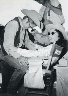 an old black and white photo of two men sitting on a chair with hats over their heads