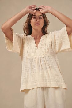 The Tulum top from Australian brand Little Lies is a perfect staple for spring/summer. Features pleated detail on the front, a flattering square sleeve and a v-neckline. This gorgeous top is an oversized fit that can be paired with your favorite pants or shorts. Semi-sheer. Materials: 100% Cotton Care: Wash with like colors; cold gentle machine wash; do not bleach; lay flat to dry; warm iron; do not tumble dry. Size Info: Model is 5'8" and is wearing a size S; relaxed fit Size Guide | Shipping Policy Chic Spring Top With Notched Neckline, Versatile Beige V-neck Top, Chic Tops With Notched Neckline For Spring, Versatile Beige V-neck Blouse, Beige V-neck Top For Summer, Effortless V-neck Blouse For Day Out, Spring Top With Notched Neckline For Day Out, Versatile V-neck Blouse For Beach, Relaxed V-neck Blouse For Day Out