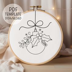 an embroidered christmas ornament on a wooden hoop with lights in the background and text overlay