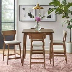 a dining table with two chairs and a vase filled with flowers