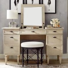 a desk with a mirror, stool and pictures on the wall in front of it