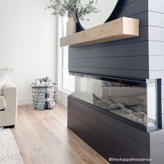 a white couch sitting next to a fireplace in a living room on top of a hard wood floor