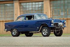 an old blue car parked in front of a building