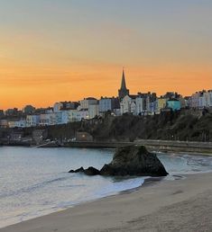 the beach is empty with no people on it at sunset or sunrise time, and there are buildings in the background