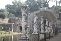 some statues are in front of a body of water