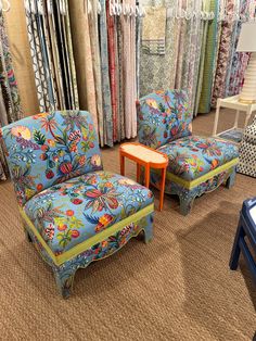 a living room filled with furniture and lots of fabrics on the walls behind it is a colorful chair and footstool