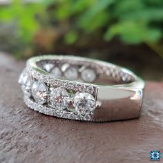 two wedding rings sitting on top of a stone slab with green plants in the background