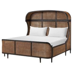 a bed with wicker headboard and white pillows on top of it's frame