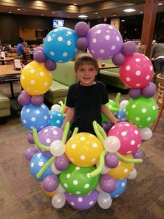 a young boy standing in front of a bunch of balloons