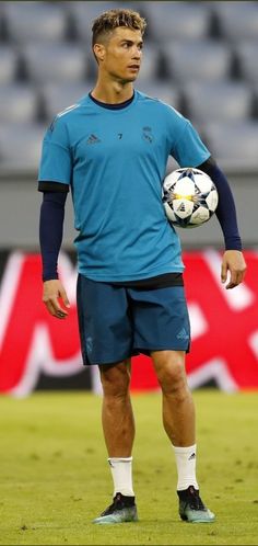 a man standing on top of a field with a soccer ball in his hand,