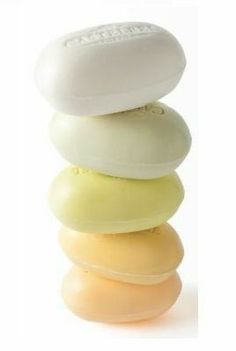 four soap bars stacked on top of each other in different colors and sizes, with one white