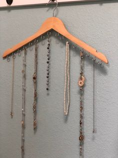 a wooden hanger with beads and necklaces hanging from it's side on a wall