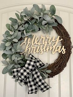 a wreath with the words merry christmas hanging on it's front door, decorated with greenery