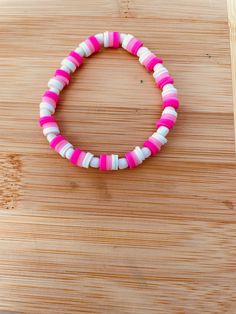 a pink and white bracelet sitting on top of a wooden table