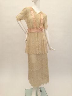 Here is a very pretty antique Edwardian cream layered lace dress with beautiful pale pink silk ribbon decoration to the bodice, waist and back of the dress. There are faux pearl embellishments to each sleeve and to the front of the skirt and bodice. The dress fastens with hooks and eyes. When laid flat the measurements are:Length: 52.5" inchesFrom underarm to underarm across: 17" inchesAcross the waist: 14.5" inchesAcross the hips: 18" inchesSleeve length: 11" inches measured from the shoulder s Feminine Beige Lace Patchwork Dress, Feminine Beige Lace Dress With Delicate Details, Feminine Delicate Lace Beige Dress, Feminine Beige Delicate Lace Dress, Beige Lace Patchwork Evening Dress, Beige Lace Patchwork Dress For Evening, Feminine Lace Vintage Dress, Cream Evening Dress With Lace Patchwork, Cream Lace Patchwork Evening Dress