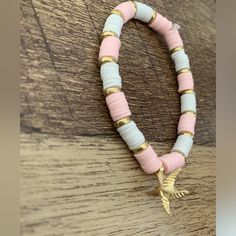 a pink and white beaded bracelet with an arrow charm hanging from it's end