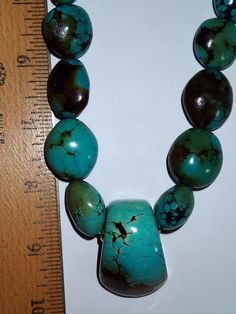 Big smooth Nugget Turquoise necklace with center chunk of turquoise. Nice greenish blue. Sterling clasp. Smooth Beads are approx. 3/4 inch long and taper down towards back ends. Center chunk is flat on back to sit well on chest, and about 1 3/4 inch long, rounded on front that tapers down to a wedge shape. The brownish matrix and slight greenish tint on the stones are wonderful. This is strung on a wire for strength Artisan Turquoise Necklace With Large Beads, Artisan Turquoise Necklace With Large Stone, Blue Turquoise Necklace With Large Pendant, Luxury Turquoise Necklace With Large Stone, Unique Turquoise Chrysocolla Beaded Necklaces, Turquoise Nugget Necklace, Turquoise Multi-strand Necklace With Large Beads, Artisan Blue Turquoise Multi-stone Necklace, Greenish Blue