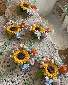 three sunflowers are sitting on top of a piece of cloth next to other flowers