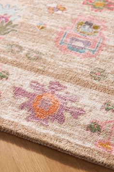 an area rug with flowers on it sitting on a wooden floor next to a vase