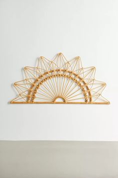 a wall sculpture made out of gold wire with an intricate design on the top and bottom