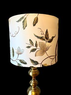 a lamp that is on top of a metal base and has leaves painted on it