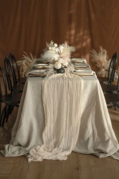 the table is set with white linens and black chairs, along with pamodia