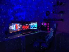 two computer monitors sitting on top of a desk in front of a blue star filled wall