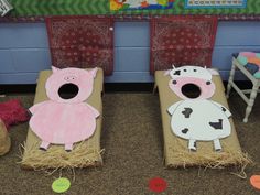 two cardboard pigs sitting on top of hay next to each other in front of chairs