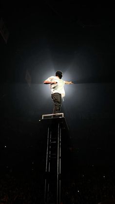 a man standing on top of a ladder in the middle of a dark room with lights