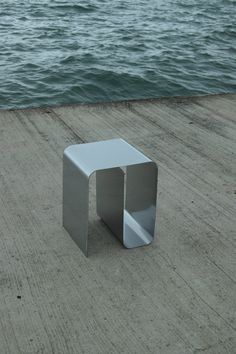 a small white table sitting on top of a wooden pier next to the ocean with water in the background