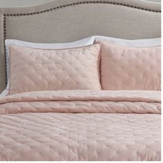 a bed with pink comforter and pillows on it