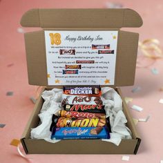 an open birthday box filled with chocolates and confetti on a pink table