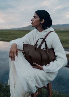 This sculptured compact tote bag featuring waves, folds, and curves can be used in two ways. Basket-style, with its sides open and straps on the outside, or As a flower-like closed bag, with its sides tucked in and its straps crossed on the inside.