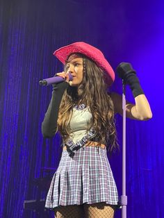 a woman with long hair wearing a red hat and holding a microphone in her hand